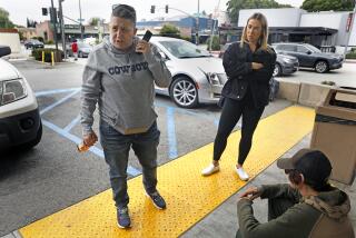 PASADENA-CA-MAY 11, 2023: Crisis interventionist Vicki Lucas, left, is accompanied by Emily Spencer, center, who works for Lucas on a freelance basis-part of a larger network of assistants that Lucas maintains for intervention work throughout the state and the country, as they provide Sherry Hill's daughter, right, with a chance to speak on a phone with Hill outside of a 7-Eleven convenience store in Pasadena on May 11, 2023. (Christina House / Los Angeles Times)