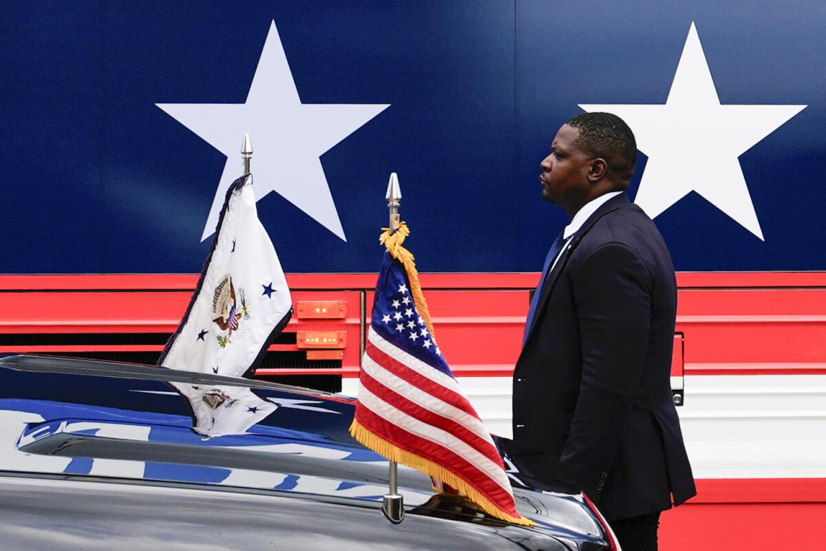 A man in a suit stands by a campaign bus.