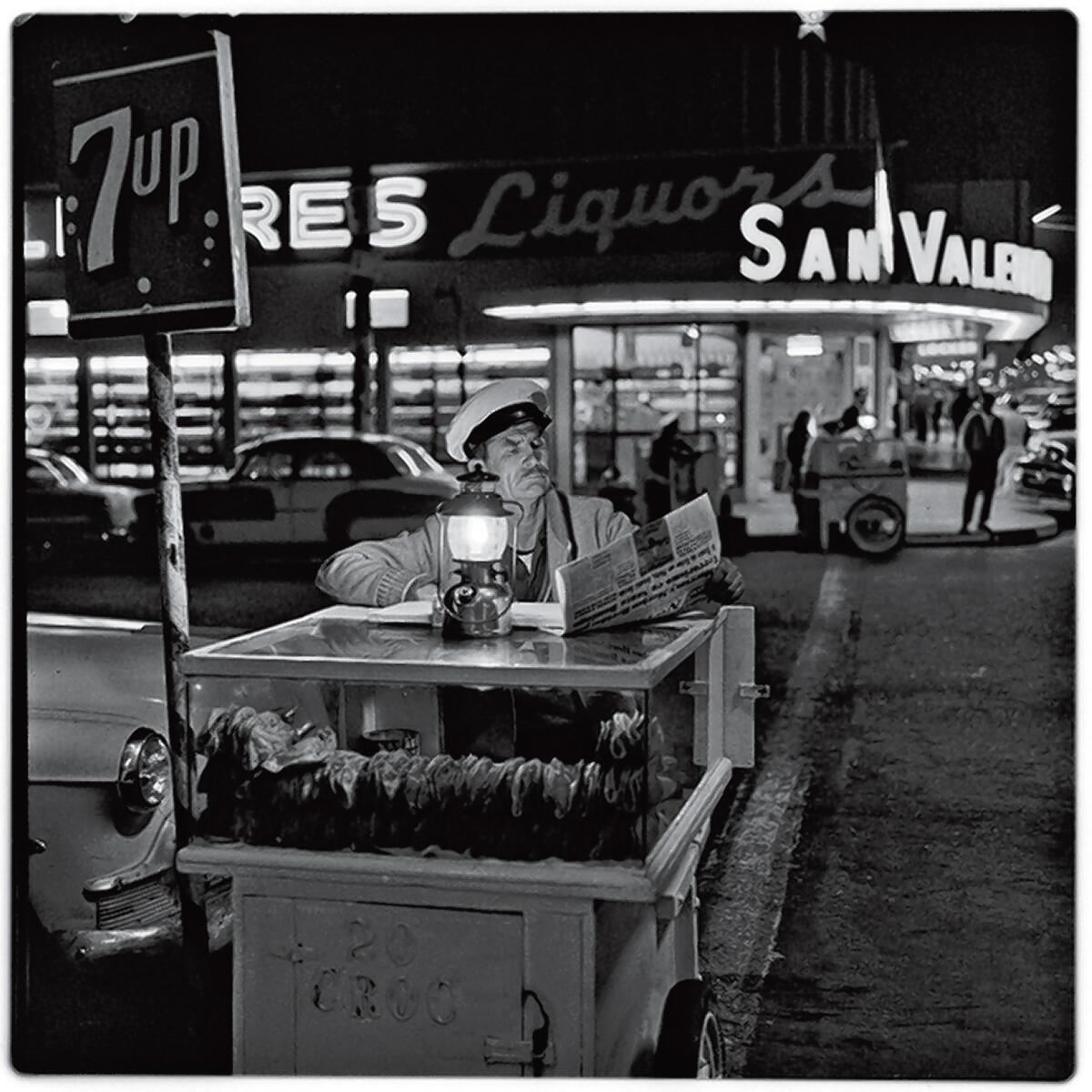 A taco vender catching up on the day’s news until the next customer shows up. Gelatin Silver Print, 1964. Photograph by Harry Crosby. Collection of Paul Ganster