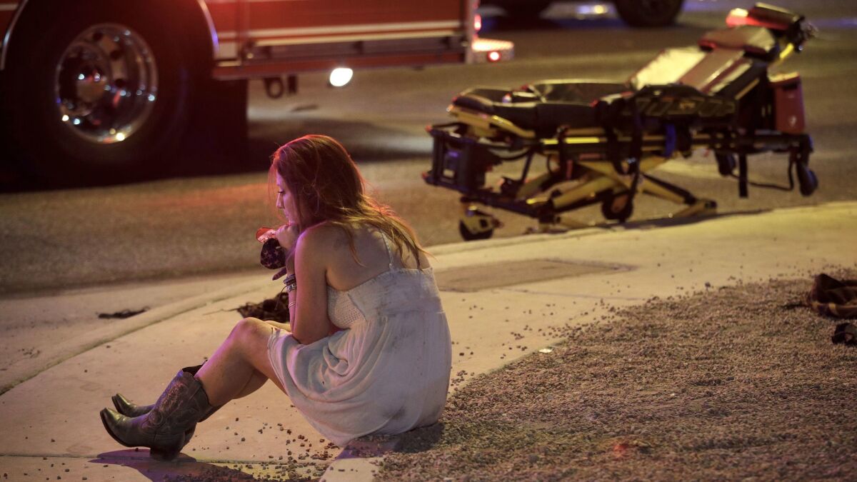 Sheri Sletten sits on a curb near the scene of the mass shooting at the Route 91 Harvest Music Festival in Las Vegas. She's holding a blood-soaked America flag bandana she used to help a victim.