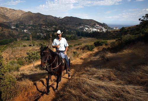 Rusty Connelly, owner of Catalina Stables, rides his horse Bruno on Monday, his last day on the job. Santa Catalina Island's only horseback riding concession has been ordered to close down by Tuesday, but the community is rallying to keep it operating.