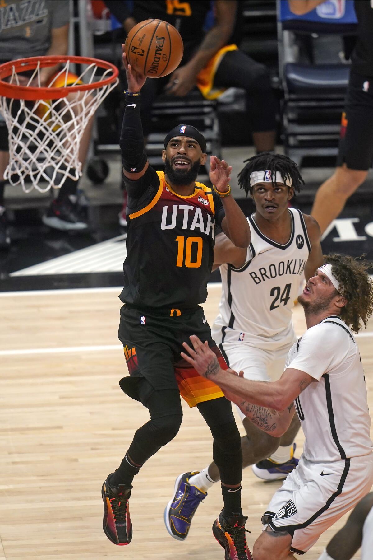 Utah Jazz guard Mike Conley (10) shoots as Brooklyn Nets' Alize Johnson (24) and Tyler Johnson, right, defend in the first half during an NBA basketball game Wednesday, March 24, 2021, in Salt Lake City. (AP Photo/Rick Bowmer)