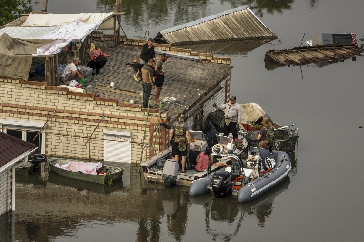 Ukrainian servicemen help residents to get down from the roof into rescue boats.
