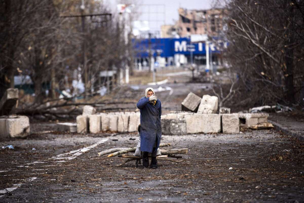 A woman collects firewood in the bombed outskirts of eastern Ukraine's Donetsk airport area. Separatists who won elections to lead the breakaway regions promised to restore peace and order after seven months of war.