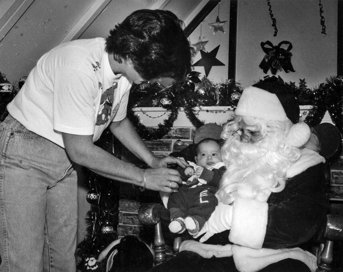 Dec. 8, 1990: Photographer Muriel Wuethrich positions 2-month-old Sergio Maya on Santa's lap before taking his picture at the Rolling Hills Plaza.