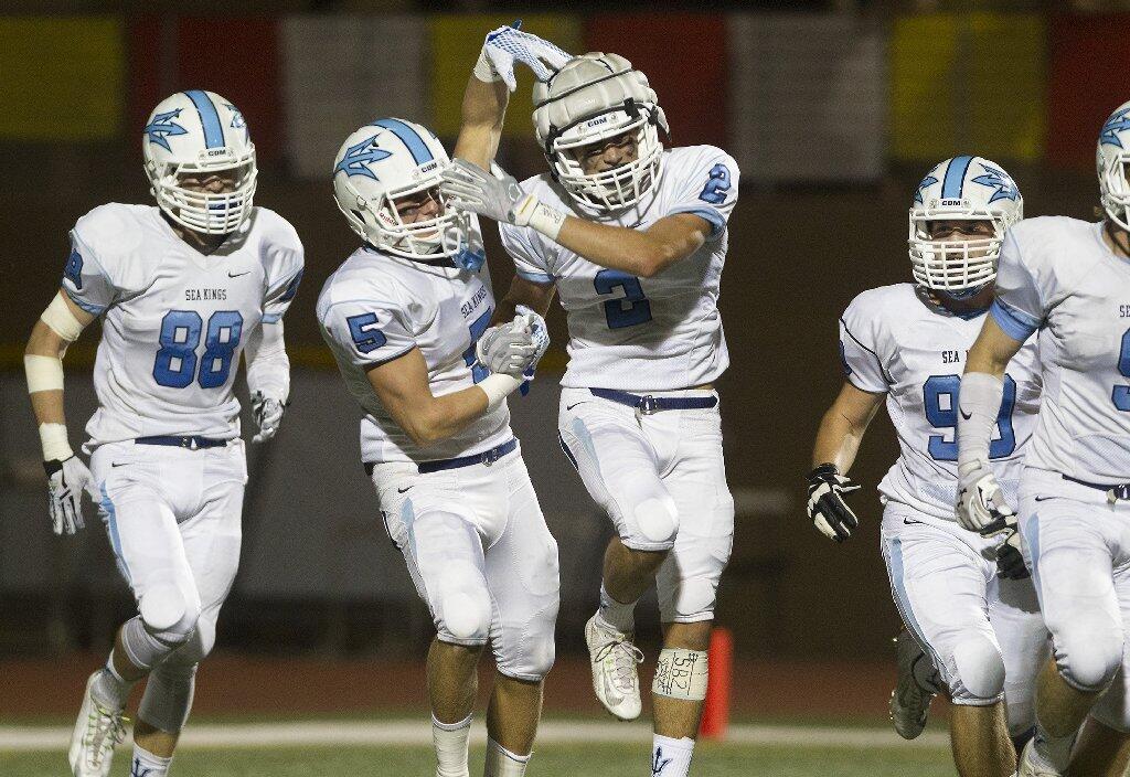 Corona del Mar High's Sutty Barbato, center, is congratulated by teammate Cameron Kormos (5) after scoring a touchdown during the first half against Woodbridge.