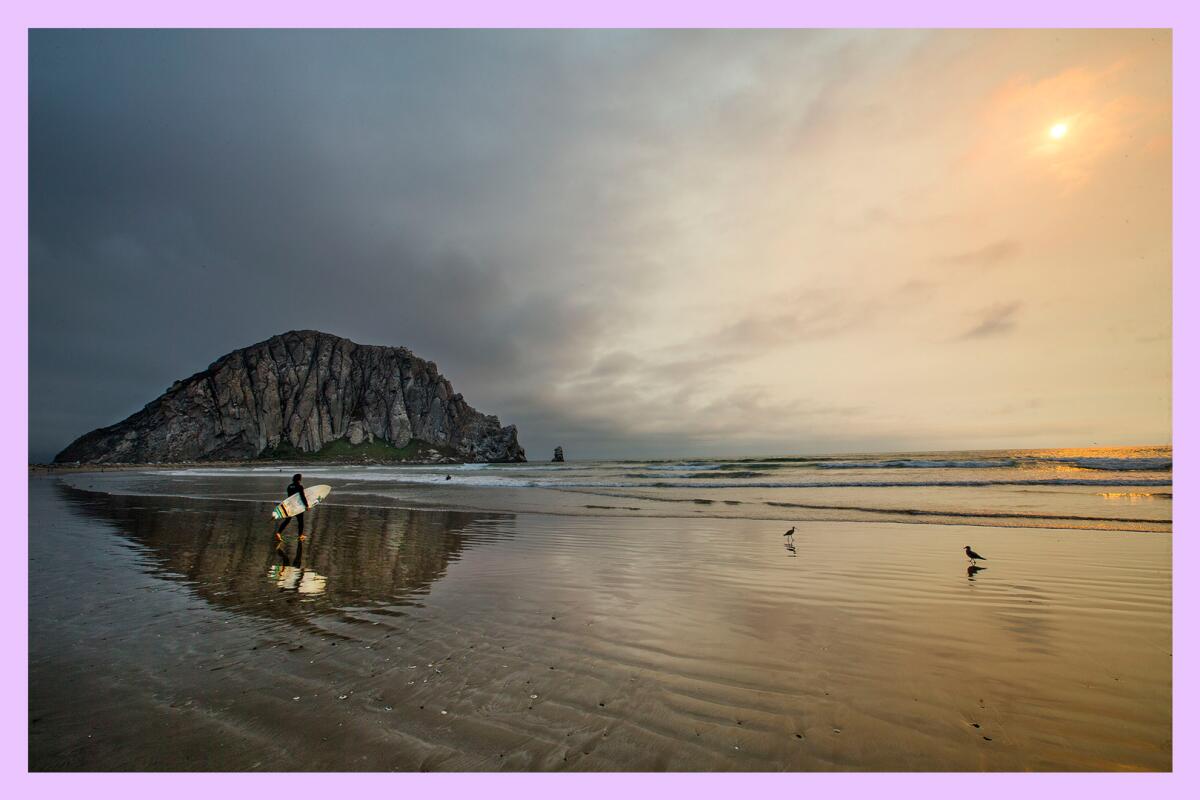 A large, almost mountainous, rock surrounded by water with the sun setting in the distance