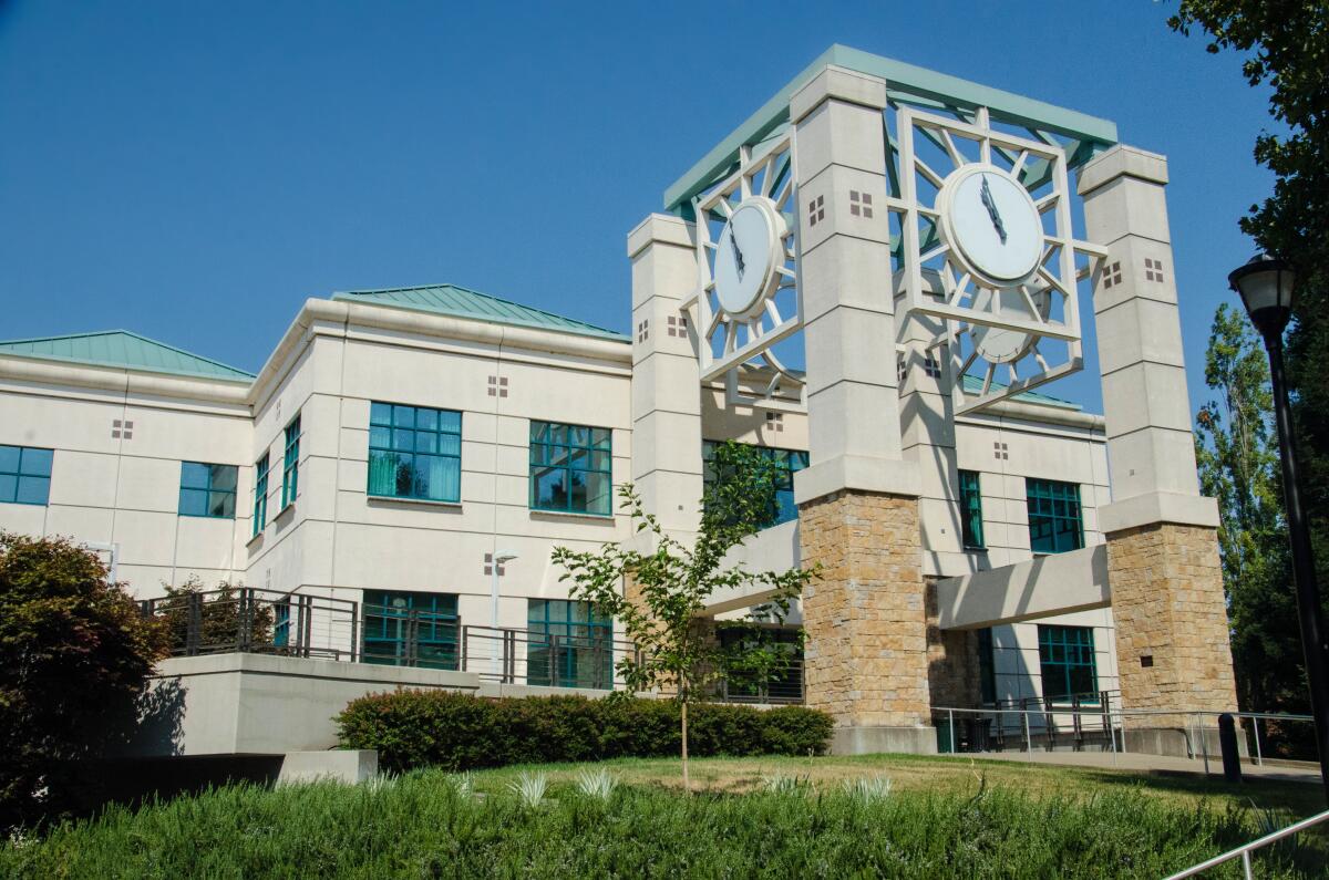 Clocks on an open structure in front of a building.