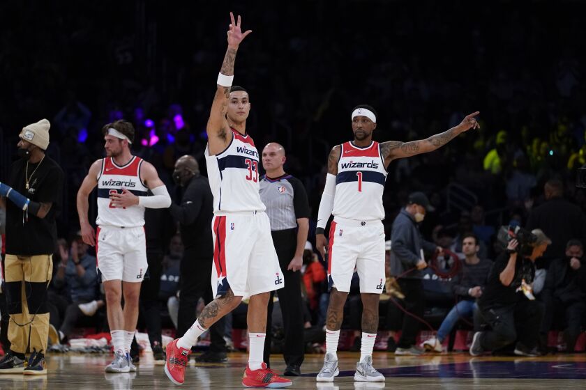 Washington Wizards forward Kyle Kuzma (33) and guard Kentavious Caldwell-Pope (1) react after a tribute to them played during the first half of an NBA basketball game against the Los Angeles Lakers in Los Angeles, Friday, March 11, 2022. Both are former Lakers players. (AP Photo/Ashley Landis)