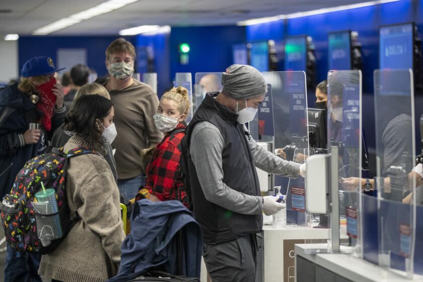 LOS ANGELES, CA - NOVEMBER 23: Travelers wearing masks get their tickets and check luggage at LAX as the Thanksgiving holiday getaway period gets underway on Monday, Nov. 23, 2020 in Los Angeles, CA. Millions of Americans are carrying on with their travel plans ahead of Thanksgiving weekend despite the CDC's urgent warnings to stay home as the number of daily cases and hospitalizations in the country continue to hit record highs. Confirmed cases in the U.S. for the disease topped 12 million on Saturday as more than 193,000 new infections were recorded in the US on Friday. This broke the previous record for the largest single-day spike on Thursday - and over 82,000 patients are now hospitalized across the country. (Allen J. Schaben / Los Angeles Times)