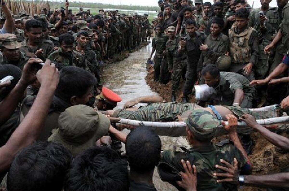 In this Tuesday, May 19, 2009 photo, Sri Lankan soldiers gather as the body of Tamil rebel leader Velupillai Prabhakaran is carried on a stretcher in Mullaittivu, Sri Lanka. Aid groups and the U.N. appealed to be allowed to survey the aftermath of the final battle of Sri Lanka's civil war and pushed for unfettered access to some 280,000 Tamils displaced from the former combat zone. (AP Photo)