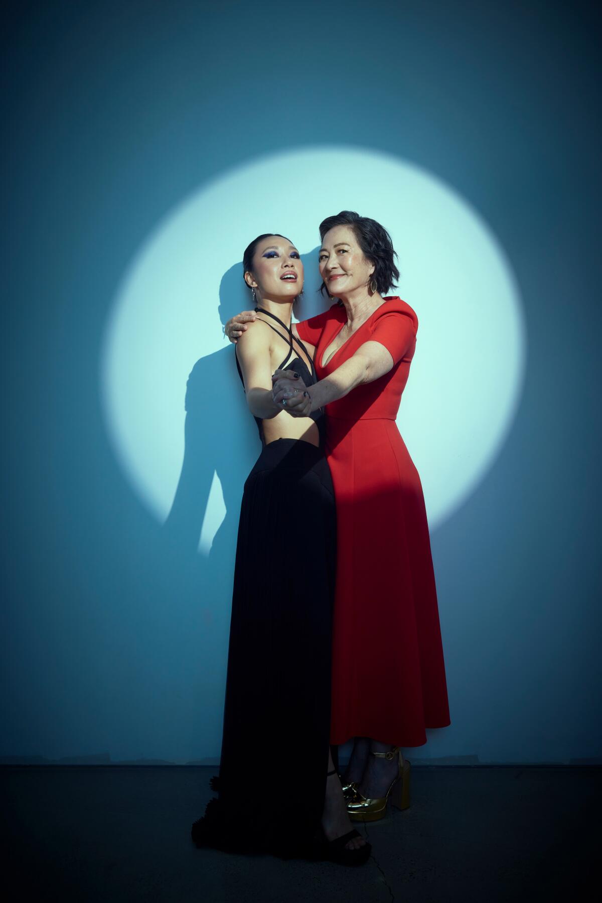 Jess Hong in a black dress and Rosalind Chao in a red dress with their hands clasped in front of them