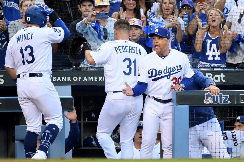 LOS ANGELES, CALIFORNIA OCTOBER 9, 2019-Dodgers manager Dave Roberts congratulates Max Muncy after his two-run home run against the Nationals in Game 5 of the NLDS at Dodger Stadium Wednesday. (Wally Skalij/Los Angeles Times)