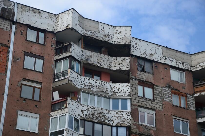 On many Sarajevo apartment buildings that were located near sniper positions in the siege of the early 1990s, scars from shelling remain, and sometimes makeshift window coverings as well.