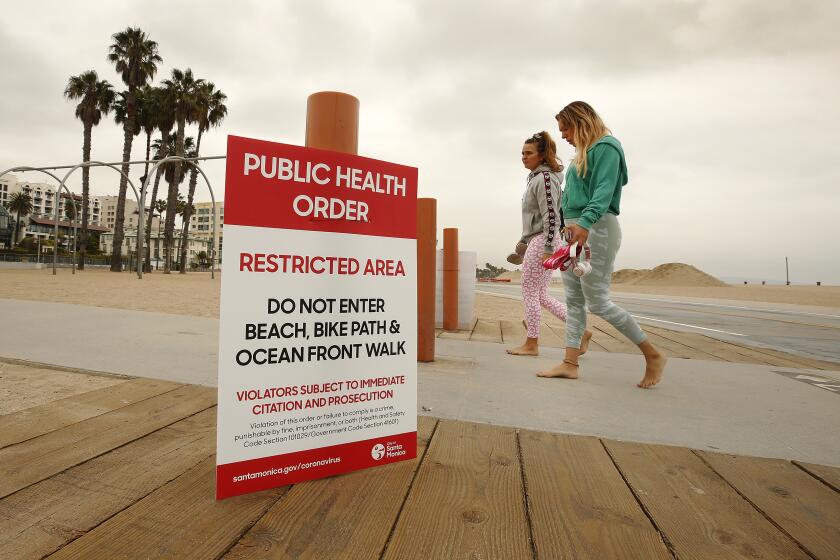 SANTA MONICA, CA - MAY 12: Kim Abt, left, and Rachel Portugal walk the beach after a social media workout Tuesday morning on the sand in Santa Monica as Los Angeles County Beaches will reopen tomorrow for active use only due to the coronavirus pandemic. Parking lots, piers and boardwalks will remain closed. Beach on Tuesday, May 12, 2020 in Santa Monica, CA. (Al Seib / Los Angeles Times)