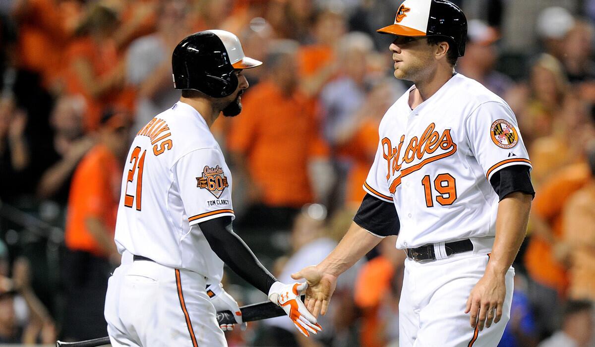 Baltimore's Nick Markakis (21) congratulates teammate Chris Davis (19) after he scored against Tampa Bay last month.