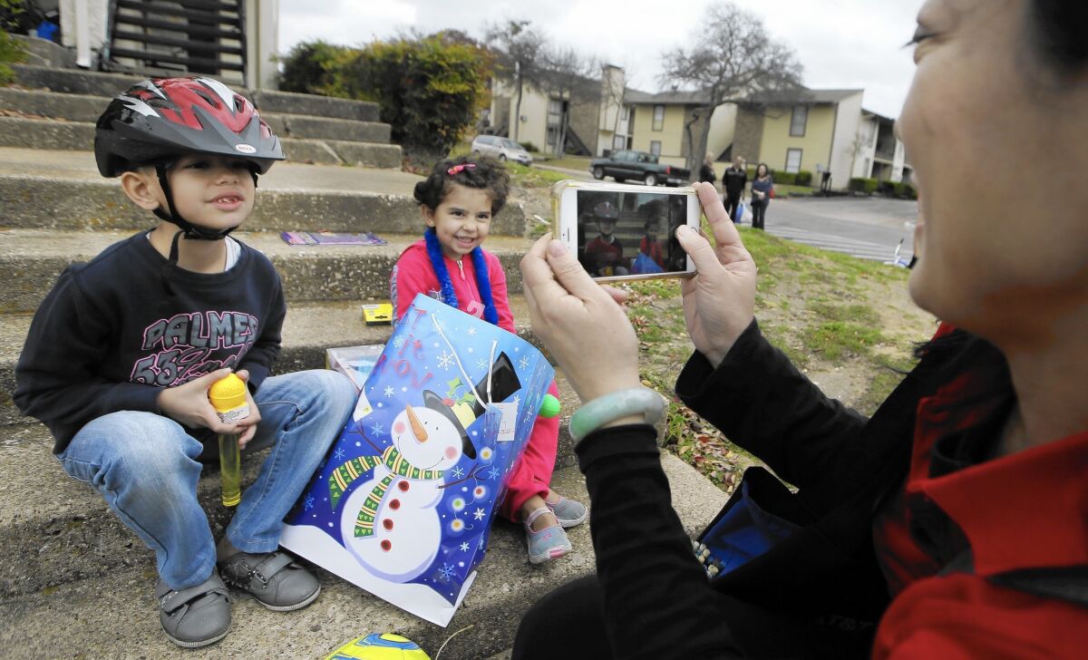 Volunteer Jessica Yang takes a photo of recently arrived Syrian refugee siblings Majerid, 7, left, and Jory, 4, outside their family's new apartment in Dallas. Texas officials have sought a court order blocking further Syrian resettlement.