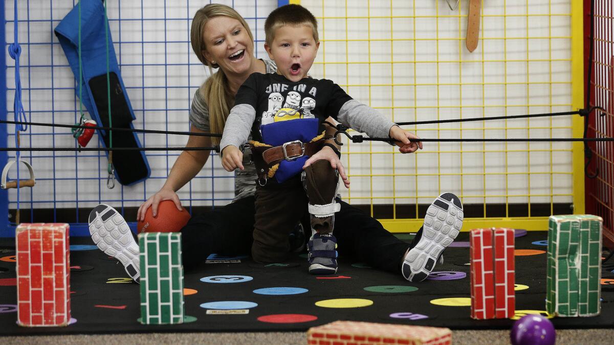 Physical trainer Kelsey Stewart reacts with Lucian Olivera as he successfully knocks over a fake brick with a ball during a session at the Simi Valley Hospital Child Development Center.
