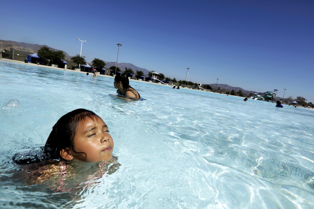 6-year-old Mia B. Mendes (foreground) and her 16-year-old aunt Alejandra Oropeza relax in a swimming lake.