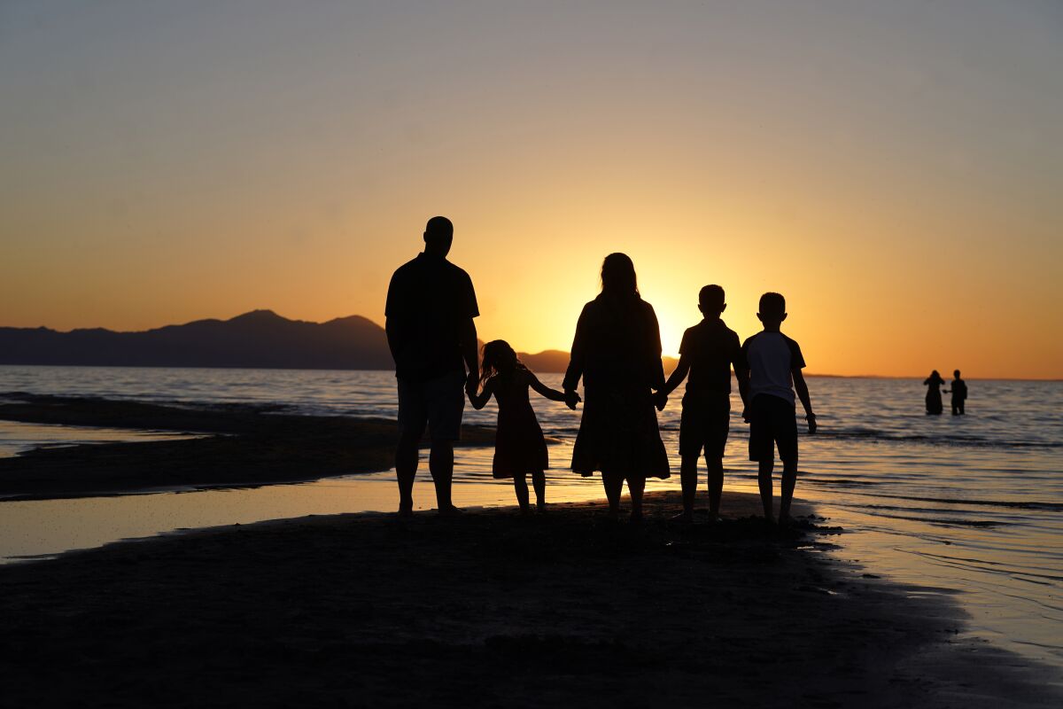 FILE - In this June 13, 2021 file photo, people hold hands as they gather at the receding edge of the Great Salt Lake to watch the sunset near Salt Lake City. The lake has been shrinking for years, and a drought gripping the American West could make this year the worst yet. (AP Photo/Rick Bowmer)