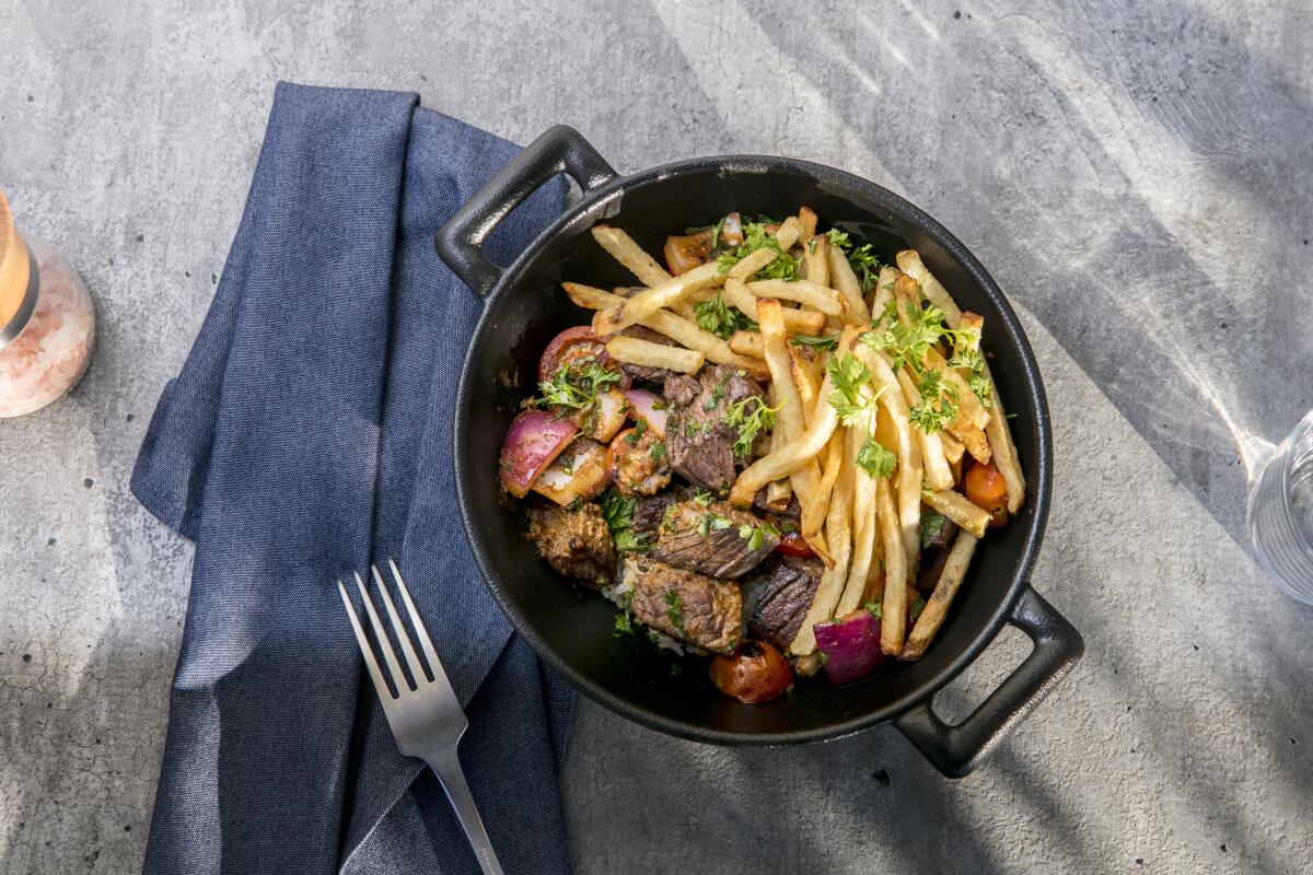 Lomo saltado at Pikoh is grass-fed hanger steak, stir-fried with tomato and onion, served with pommes frites and over seasoned rice.