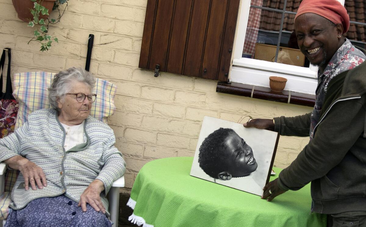 Eric Baranyanka, right, and his foster mother, Emma Monsaert, look at a photo of Eric as a young boy in Lembeek, Belgium. 