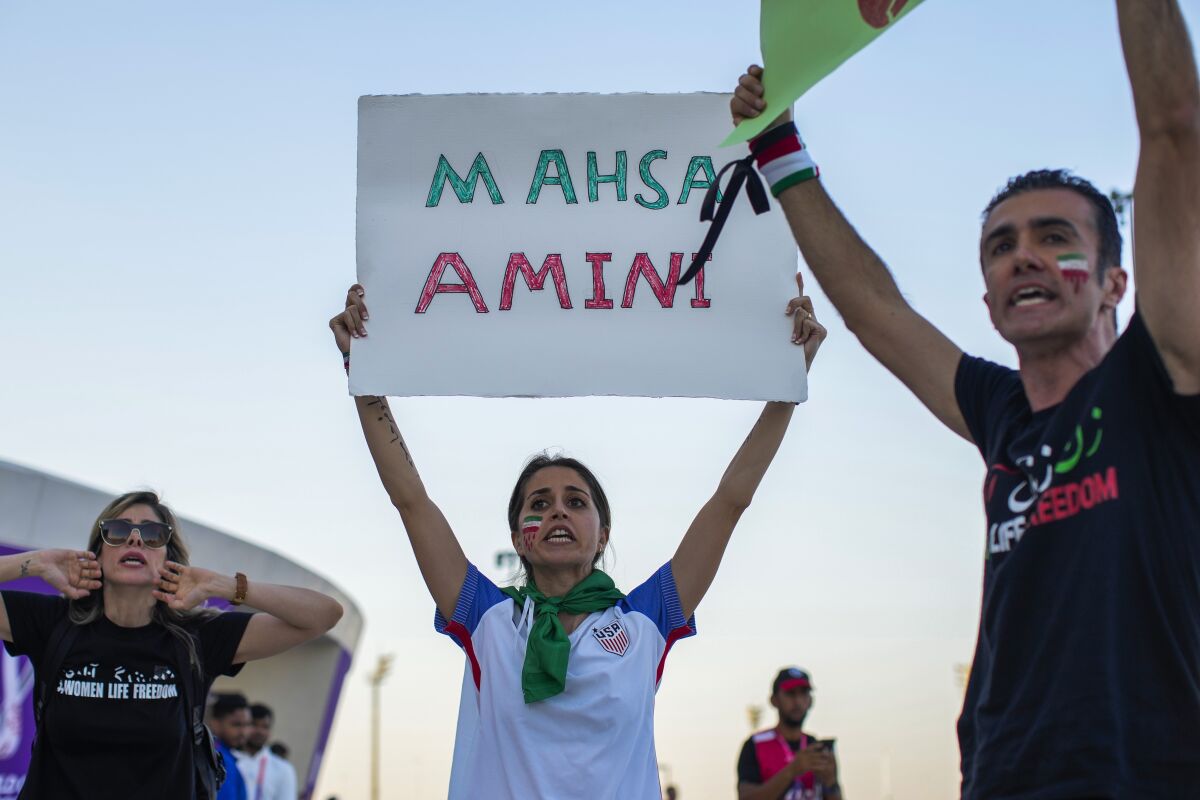 Una mujer sostiene un cartel con el nombre de Mahsa Amini, una mujer que murió mientras estaba detenida
