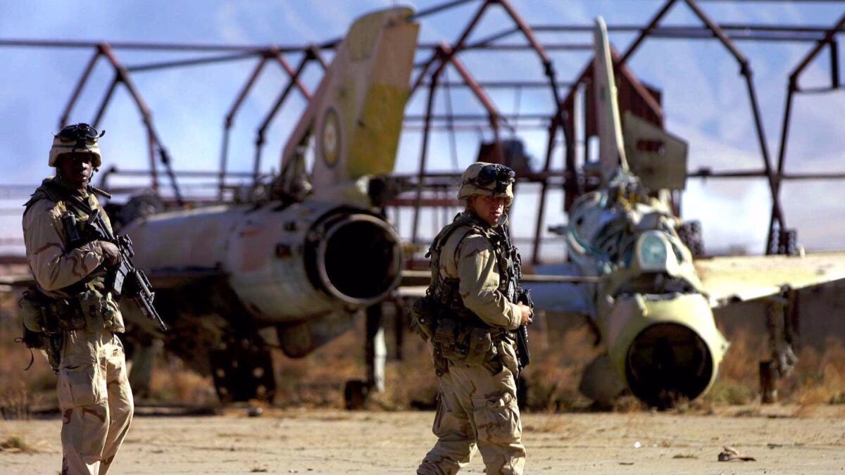 In December 2001, U.S. Army soldiers from the 10th Mountain Division patrol an airfield littered with Soviet MiG fighters abandoned at the end of the Soviet-Afghan conflict, within Bagram air base, about 25 miles north of the Afghan capital, Kabul.