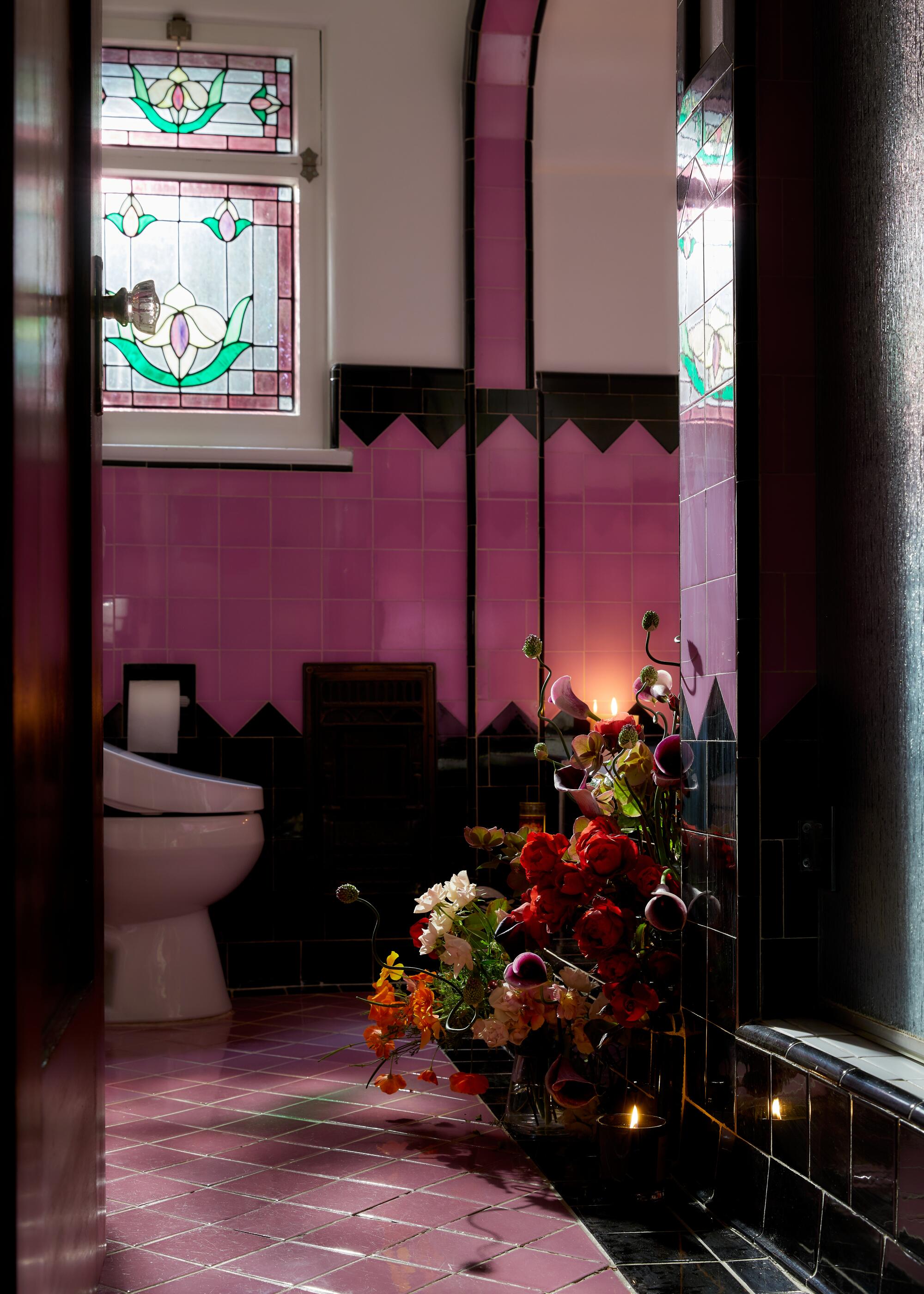 A richly tiled bathroom holds a floral art installation.