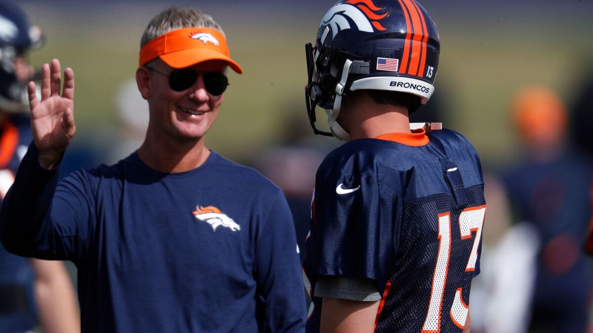 Denver Broncos offensive coordinator Mike McCoy (left) chats with quarterback Trevor Siemian during training camp in Englewood, Colo.