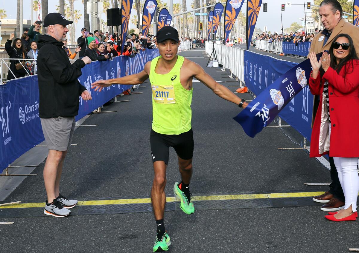 Jason Yang of Los Angeles, breaks the tape to win the Surf City Marathon in 2:29:01 on Sunday morning.
