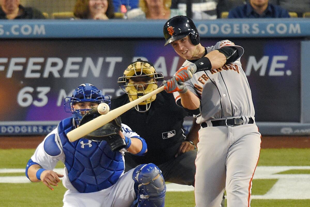 Buster Posey, de los Gigantes de San Francisco (derecha), conecta un a grand slam ante el catcher de los Dodgers de Los Ángeles Yasmani Grandal y el árbitro de plato Laz Diaz, en el tercer inning del juego entre ambos equipos, el 19 de junio de 2015.