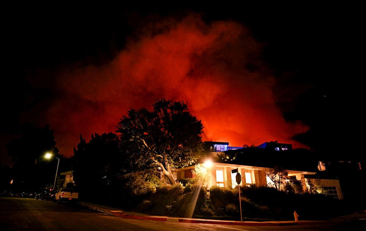 Smoke and flames from the Palisades fire seen behind a house on Corda Drive on Friday.
