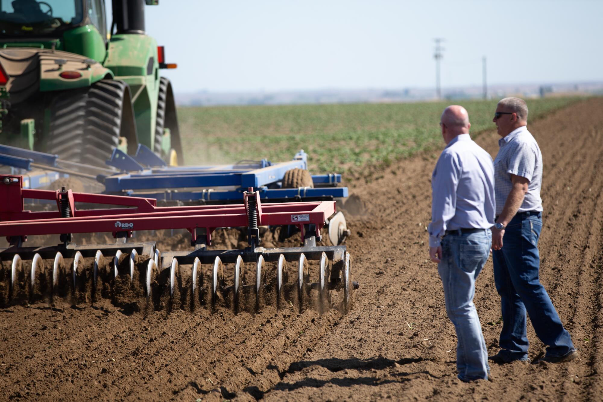 Dale Lathim, left, executive director of the Potato Growers of Washington, and farmer Mike Pink watch as 300 acres of Ranger potatoes are plowed up in a field in Eltopia, Wash.