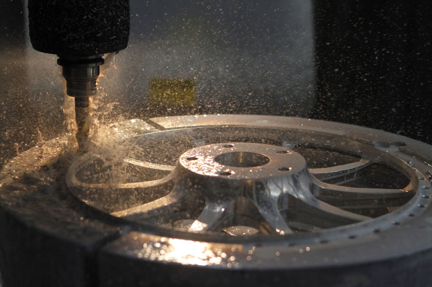 Cooling liquid splashes around as an automated cutter shapes an aluminum wheel at HRE Performance Wheels.