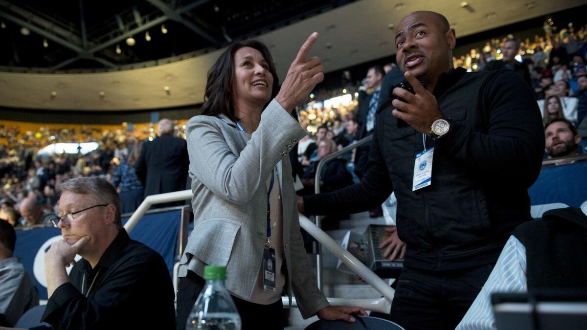 West Coast Conference Commissioner Gloria Nevarez talks with Oronde Taliaferro, an NBA scout for the Pistons, before a game.