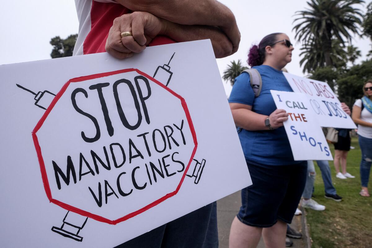 Anti-vaccination protesters hold signs during a rally in Santa Monica on Aug. 29. 
