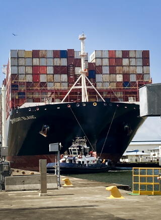 A huge black ship filled with cargo containers
