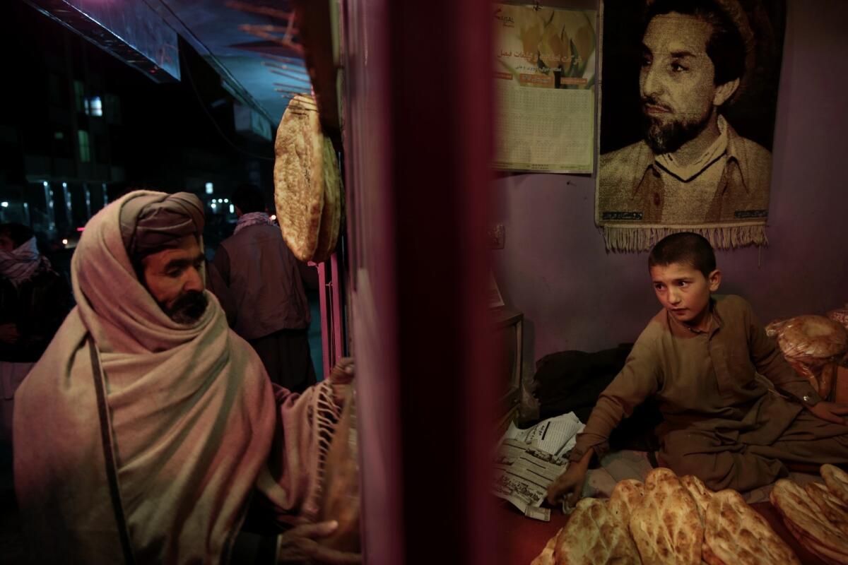 Sami, right, continues working until the evening, when people buy bread on their way home from their jobs. Child labor is illegal in Afghanistan for those under 14, but it is pervasive because of extreme poverty and inadequate law enforcement.