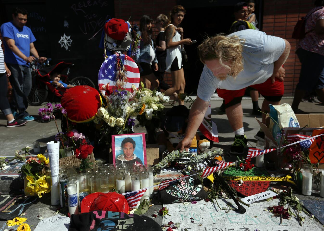 Bruce Chartier, 30, places sage on a memorial for his friend Brendon Glenn in Venice.