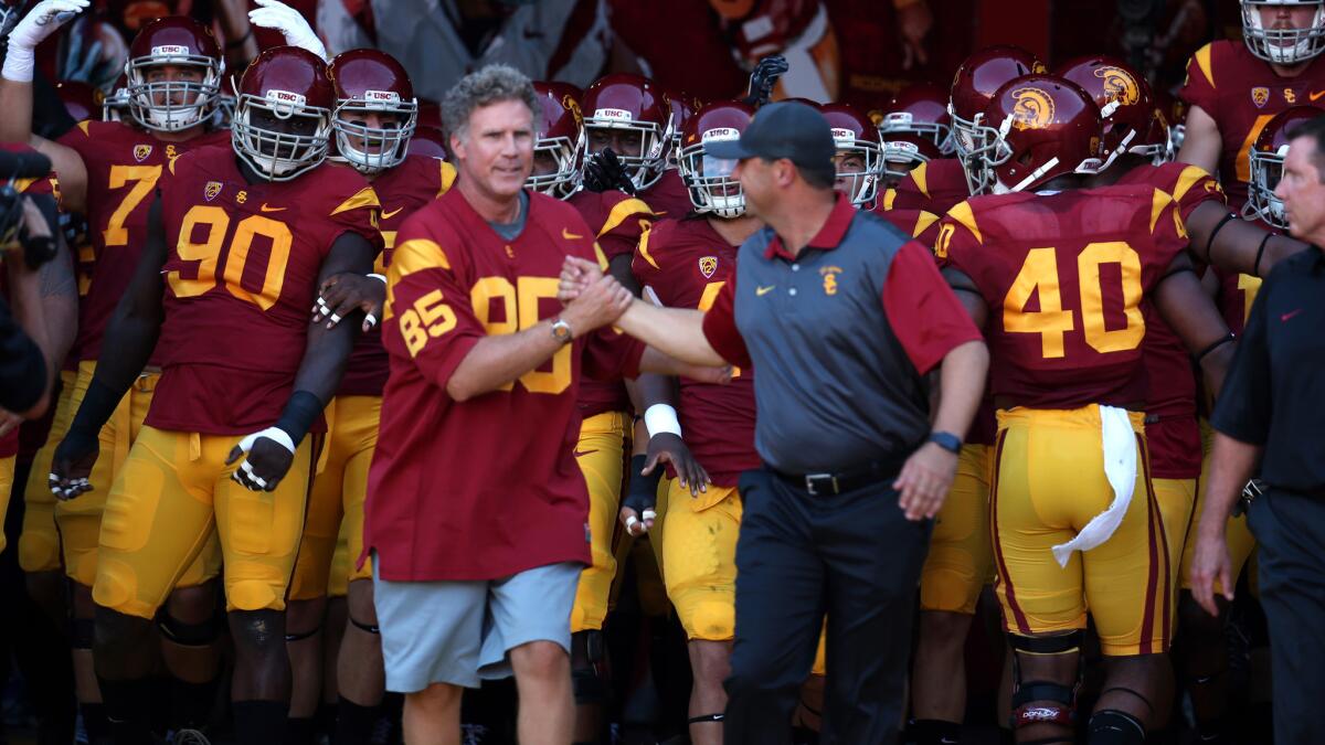 Will Ferrell, left, and USC Coach Steve Sarkisian lead the Trojans out of the Coliseum tunnel before their Pac-12 Conference game against Stanford on Saturday.