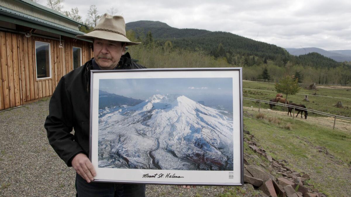 Mark Smith, owner of the Eco Park Resort, holds a photo of Mt. St. Helens on his property near the volcano. Smith's family owned and operated the Spirit Lake Lodge until it was destroyed when Mt. St. Helens erupted on May 18, 1980.