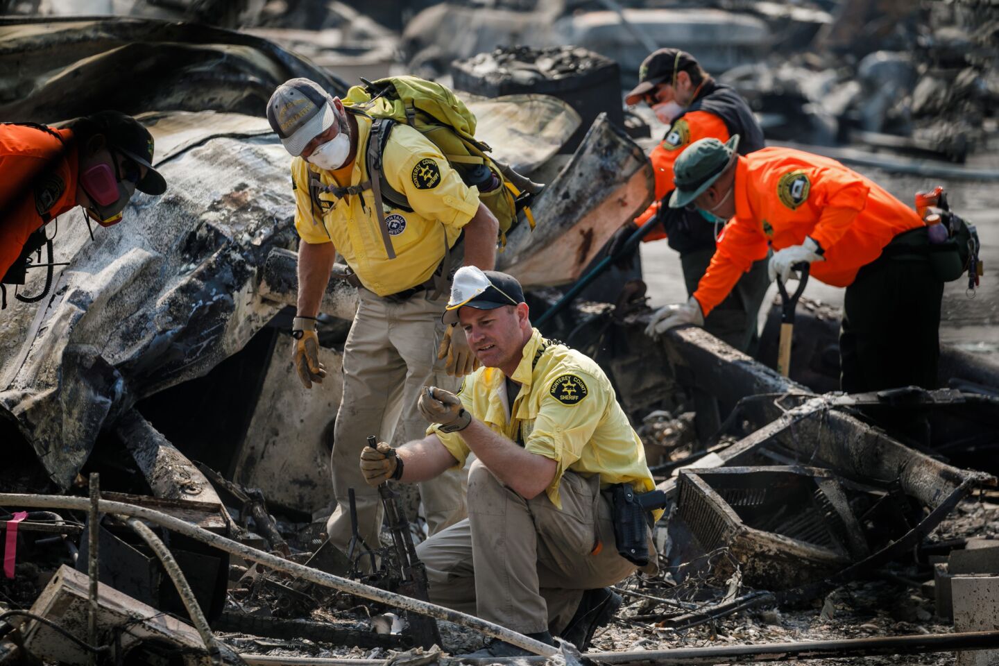 A worker pulls out a firearm from the burned wreckage as search team members look through the debris at the Journey's End Mobile Home Park in Santa Rosa.