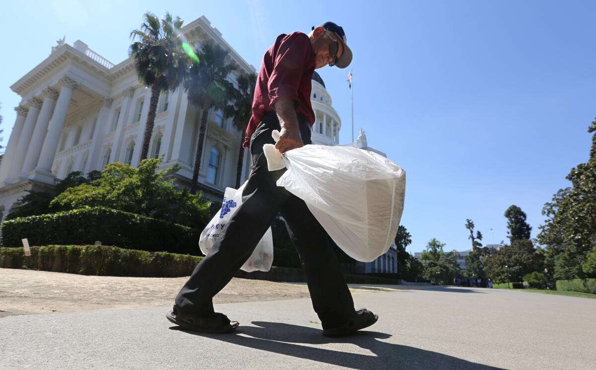 A man carries plastic single-use bags past the Capitol in Sacramento on Aug. 12, 2014.