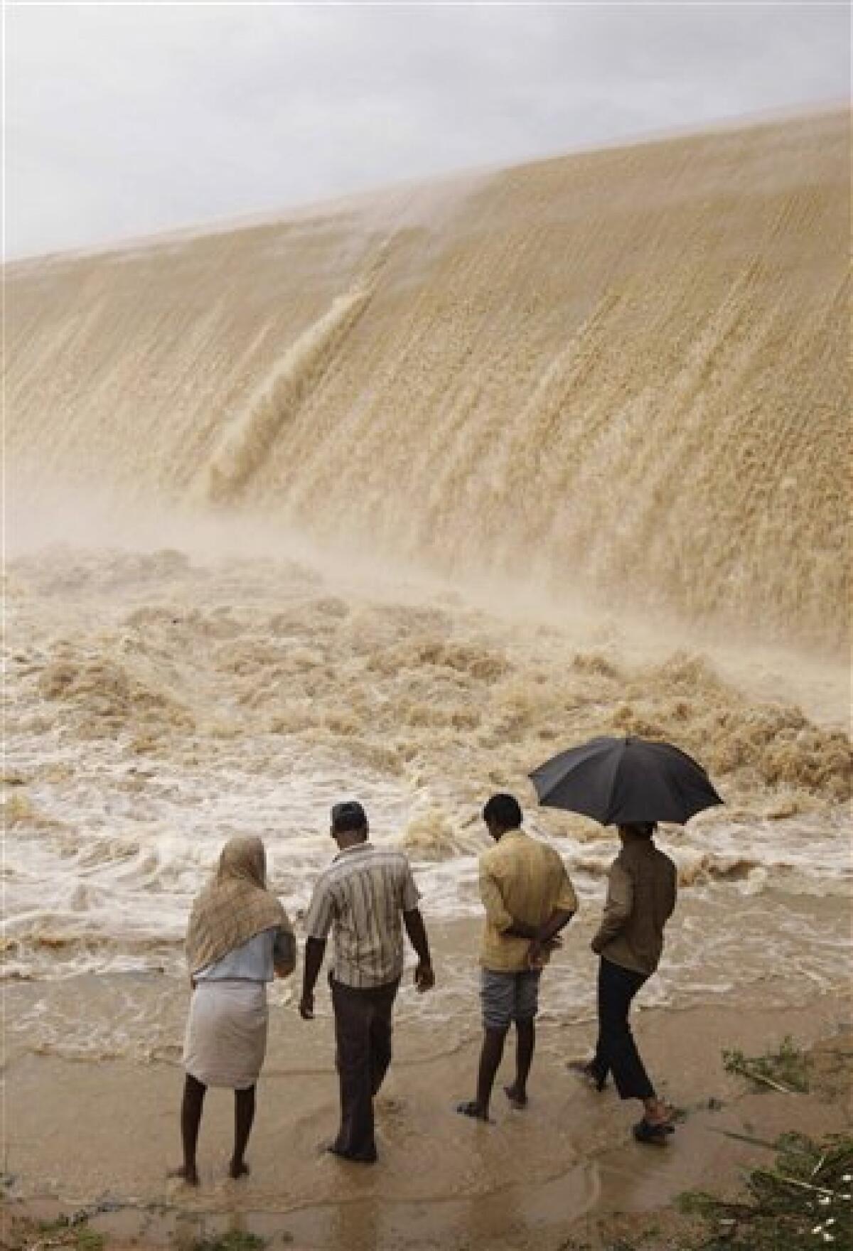 People look at an overflowing dam in Dindi, in Andhra Pradesh state, India, Thursday, Oct. 1, 2009. Torrential rains destroyed hundreds of homes and caused heavy flooding in southern India, killing at least 15 people and forcing thousands to flee to higher ground, an official said Thursday. The late monsoon flooding in the past two days also damaged roads and inundated rice crops over an area of nearly 120 square miles (300 square kilometers) in Andhra Pradesh state. (AP Photo/Mahesh Kumar A.)