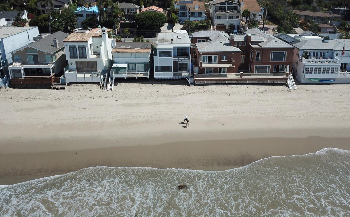 People walk along the shoreline in Malibu behind the house owned by actors Jeff and Beau Bridges that’s received a tax break for inherited property.