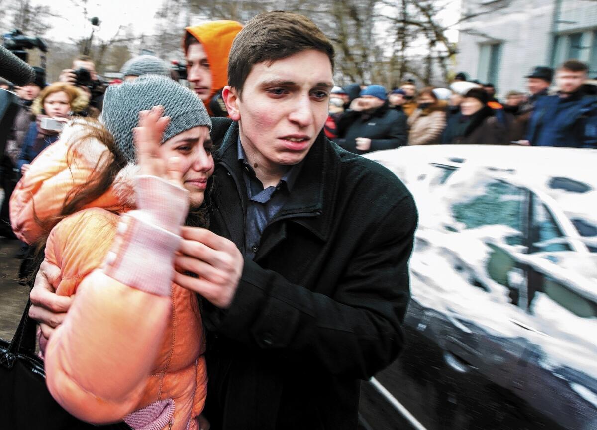 A girl, left, is hugged by a relative after she leaves the Moscow high school where a shooting took place Monday. A 15-year-old student killed two adults and held a class of 29 captive until his father persuaded him to release those in the room, officials said.