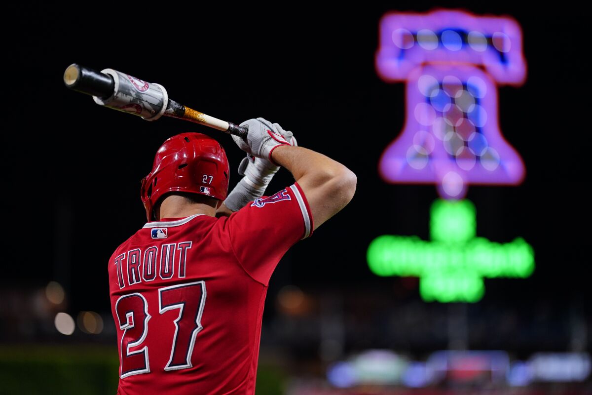 A view from behind of Angels' Mike Trout preparing to swing his bat with a neon Liberty Bell in the background