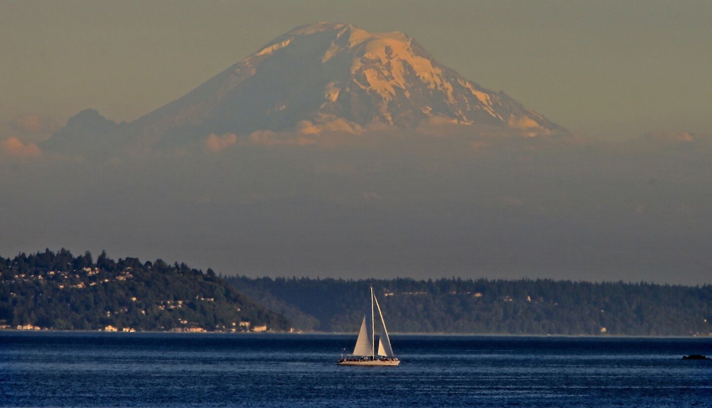 A sailboat heads out from Seattle with Mt. Rainier in the background on a beautiful summer evening.