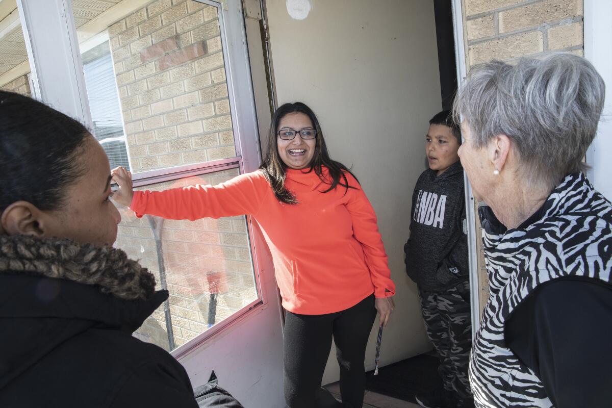 Cherice Chávez, centro, habla con la organizadora de campo Brittany James, izquierda, y la encuestadora Allyson Gottesman, derecha, de la campaña de Michael R. Bloomberg frente a su casa el sábado en Wheat Ridge, Colorado. El hijo de Chávez, Nicholas Vigil, de 11 años, escucha la conversación.